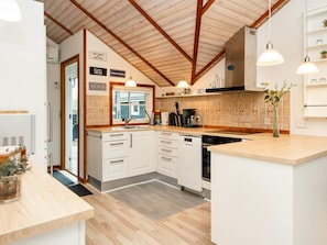 A modern kitchen with white cabinets, a wooden countertop, and a tiled backsplash.