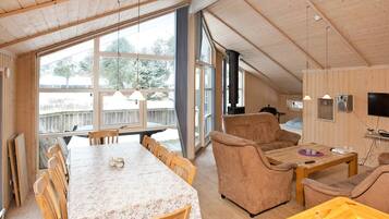 Interior acogedor de una cabaña con comedor, asientos, chimenea y televisor.