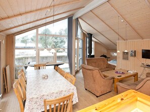 A cozy cabin interior with a dining area, seating, a fireplace, and a television. - 4 Star Holiday Home in Rodby (Rodby)