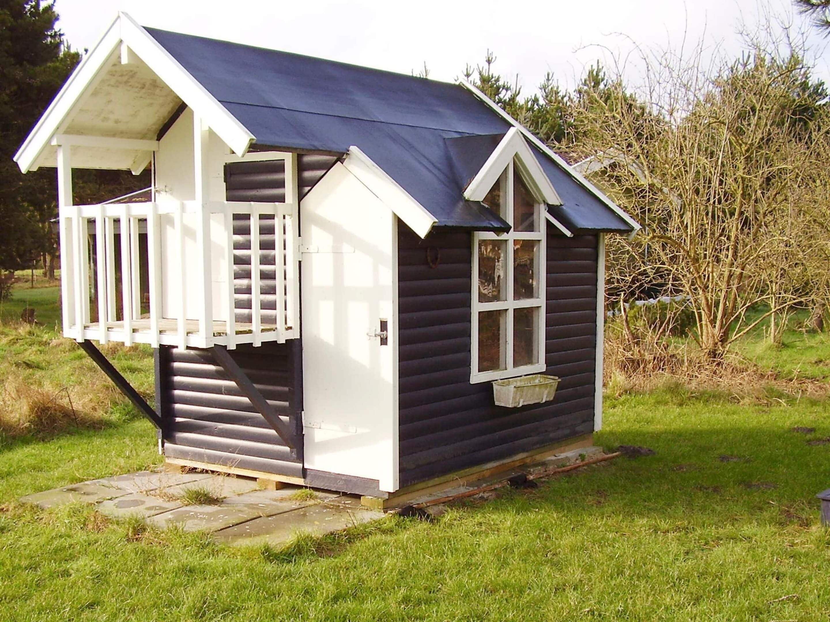 Ein kleines, einstöckiges Holzhaus mit Veranda und Fenster.