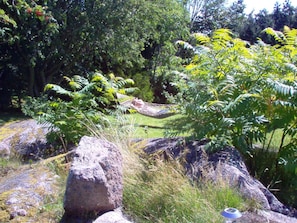 A garden with a hammock, rocks, and dense foliage. - Spacious Holiday Home in Allinge Bornholm near Sea (Allinge)