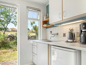 Una cocina con ventana, un lavamanos, una cafetera y un lavavajillas.