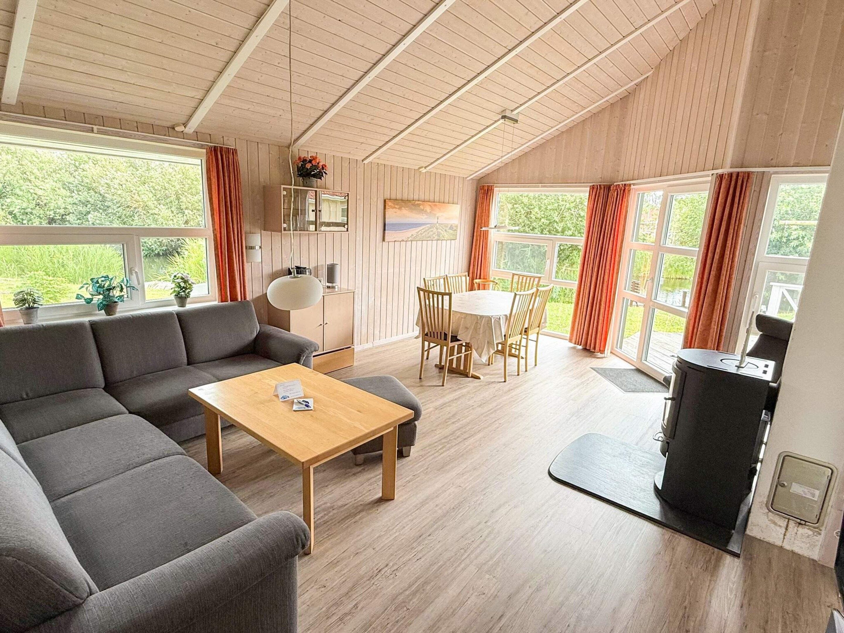 A spacious living area with a sofa, a dining table, and chairs, a ceiling fan, and a view of the outdoors.