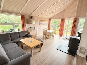 A spacious living area with a sofa, a dining table, and chairs, a ceiling fan, and a view of the outdoors. - Holiday Home in Otterndorf (Otterndorf)