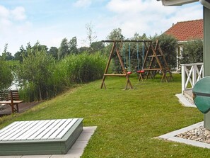 A grassy outdoor area with a swing set and a wooden bench. - Holiday Home in Otterndorf (Otterndorf)