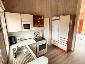 Een kleine keuken met een magnetron, fornuis, oven en een koelkast.