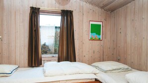 Una stanza con due letti a castello in legno, una finestra con tende e un quadro appeso al muro.