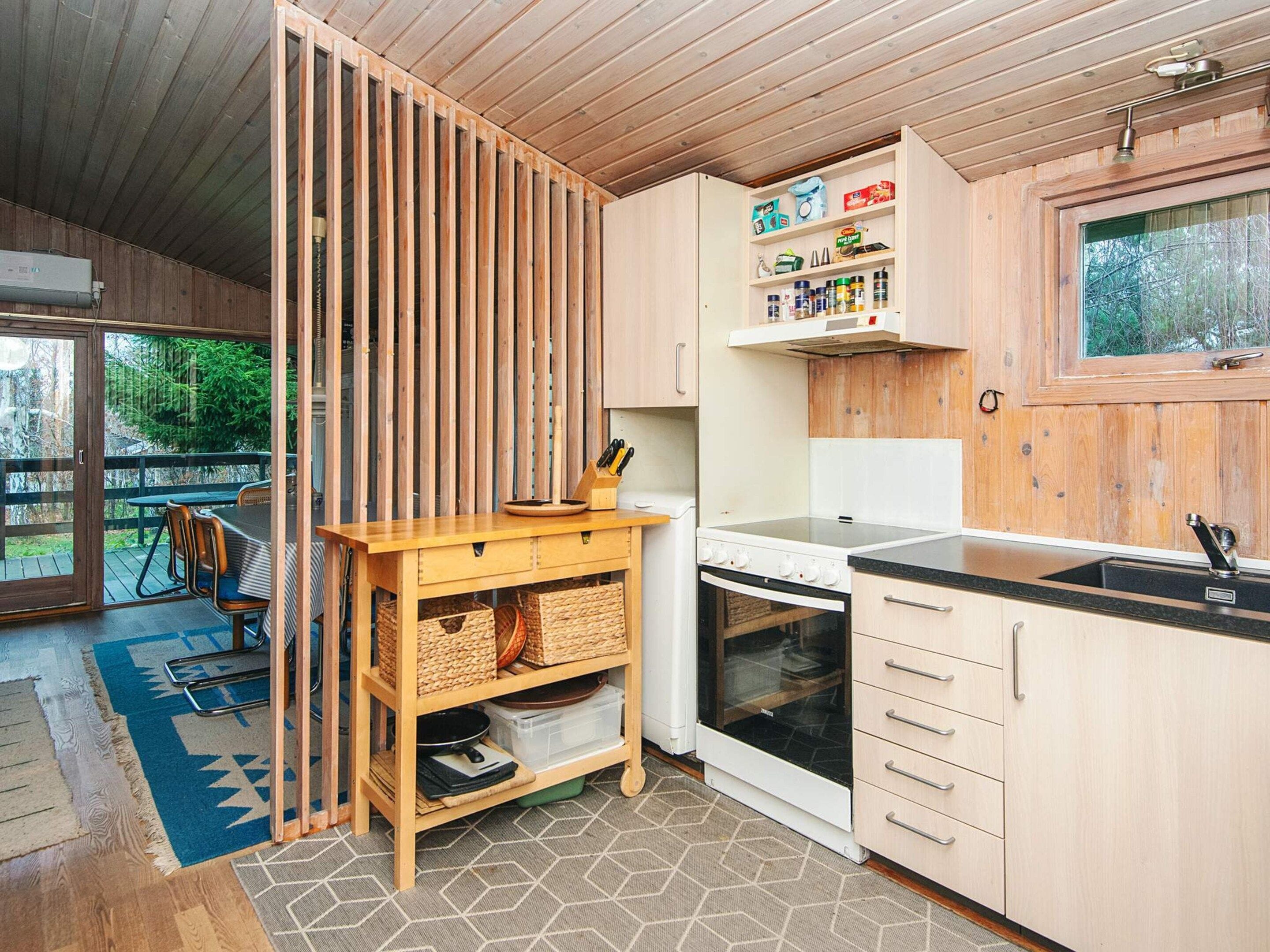 Une cuisine moderne avec des meubles en bois, un four encastré et un coin repas comprenant une table et des chaises.