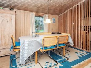 A wooden-paneled room with a dining table, chairs, and a window.