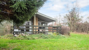 A cabin with a porch, a covered outdoor seating area, and a grassy yard.