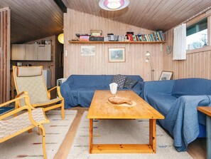 A cozy room with a blue sofa, wooden table, and a bookshelf filled with books.