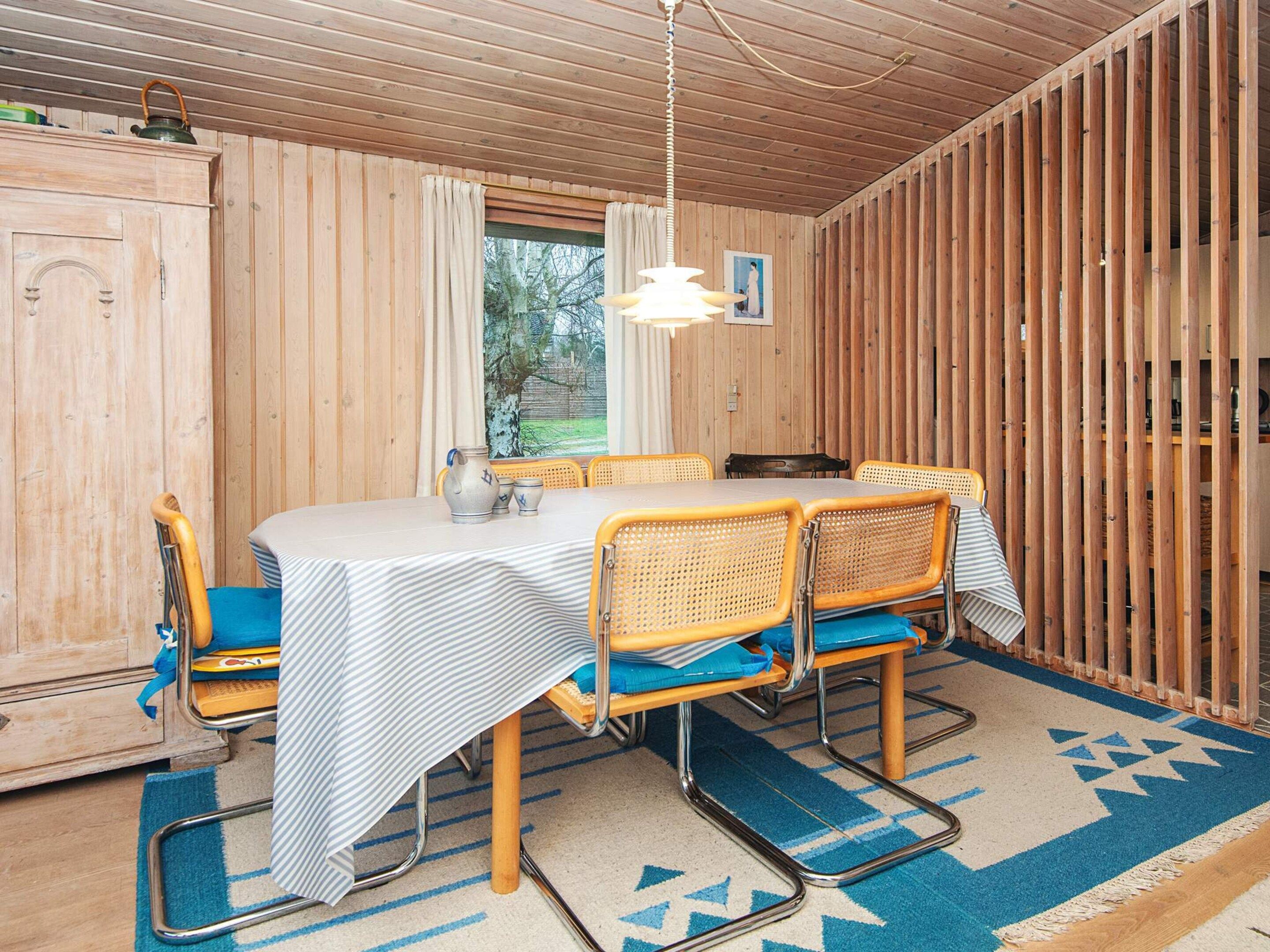 Une pièce aux murs lambrés, avec une table à manger, des chaises et une fenêtre.