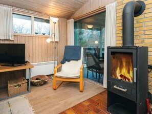 Ein gemütliches Zimmer mit Kamin, Fernseher und bequemen Sessel.