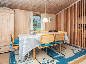 A wooden-paneled room with a dining table, chairs, and a window.