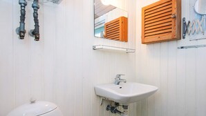 Un bagno con il water bianco, un lavabo con uno specchio sopra e persiane in legno.
