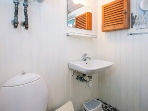 Ein Badezimmer mit einer weißen Toilette, einem Waschbecken mit Spiegel darüber und Holzfensterläden.