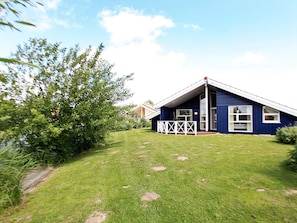 A single-story house with a sloped roof, a fenced front yard, and a clear sky. - Holiday Home in Otterndorf (Otterndorf)