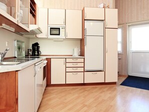 A kitchen with wooden cabinets, a microwave, a refrigerator, a coffee maker, and a sink. - Holiday Home in Otterndorf (Otterndorf)
