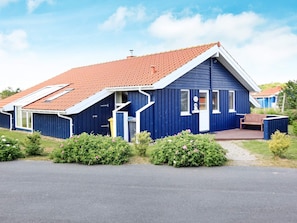 A blue building with a red-tiled roof, a front porch, and a small garden area. - Holiday Home in Otterndorf (Otterndorf)