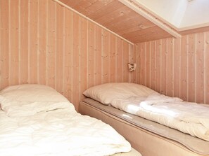 A room with two beds, wooden walls, and a sloped ceiling. - Holiday Home in Otterndorf (Otterndorf)