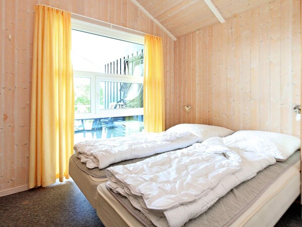 Una habitación con cama, cortinas y ventana con vista a muebles de exterior.
