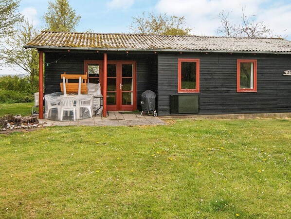 A small black building with a tiled roof, a wooden bench, and a covered outdoor seating area.