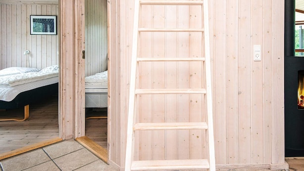 Un interior de madera con una escalera, una cama y un cuadro en la pared.