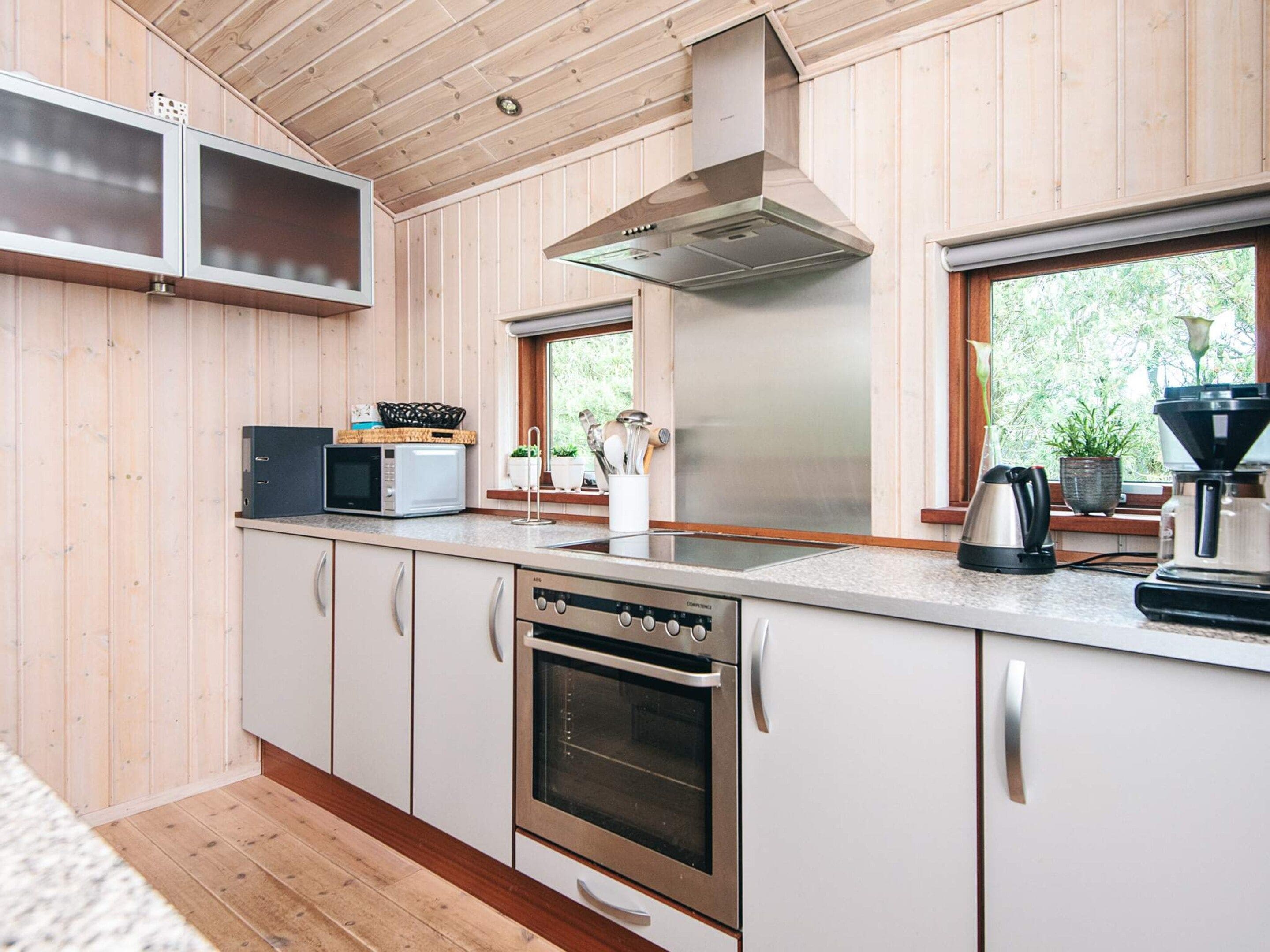 A modern kitchen with wooden paneling, stainless steel appliances, and a window providing natural light.