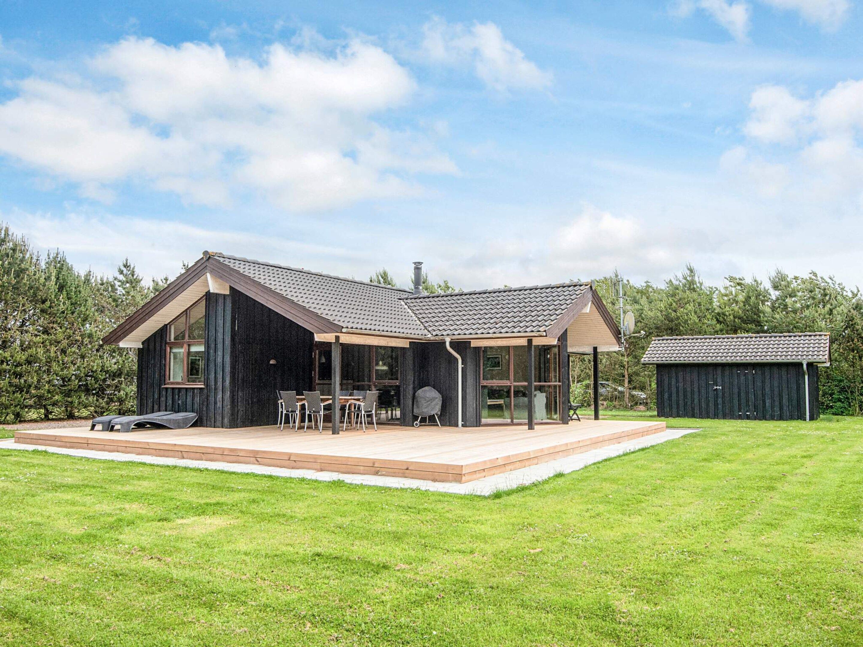 Une maison moderne dotée d’un grand patio, d’un espace repas extérieur couvert et d’un garage séparé.
