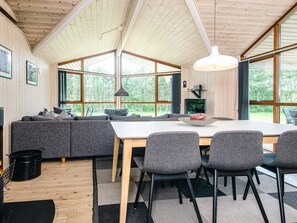 A modern interior with a wooden ceiling, large windows, a dining area with a table and chairs, and a seating area with sofas. - 4 Star Holiday Home in Hemmet (Hemmet)