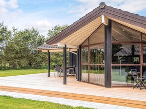 A modern outdoor patio with a wooden deck, a covered seating area, and a glass-enclosed structure. - 4 Star Holiday Home in Hemmet (Hemmet)