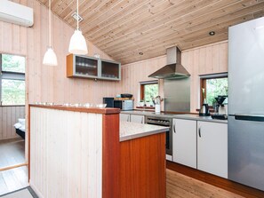 Cozinha moderna com paredes de madeira, uma ilha central, eletrodomésticos de aço inoxidável e iluminação pendente.
