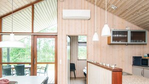 Una cocina moderna con paredes de madera, un comedor con mesa y sillas, y vistas al exterior.