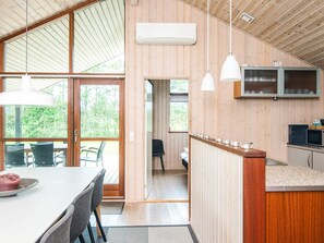 A modern kitchen with wooden walls, a dining area with a table and chairs, and a view of the outdoors. - 4 Star Holiday Home in Hemmet (Hemmet)