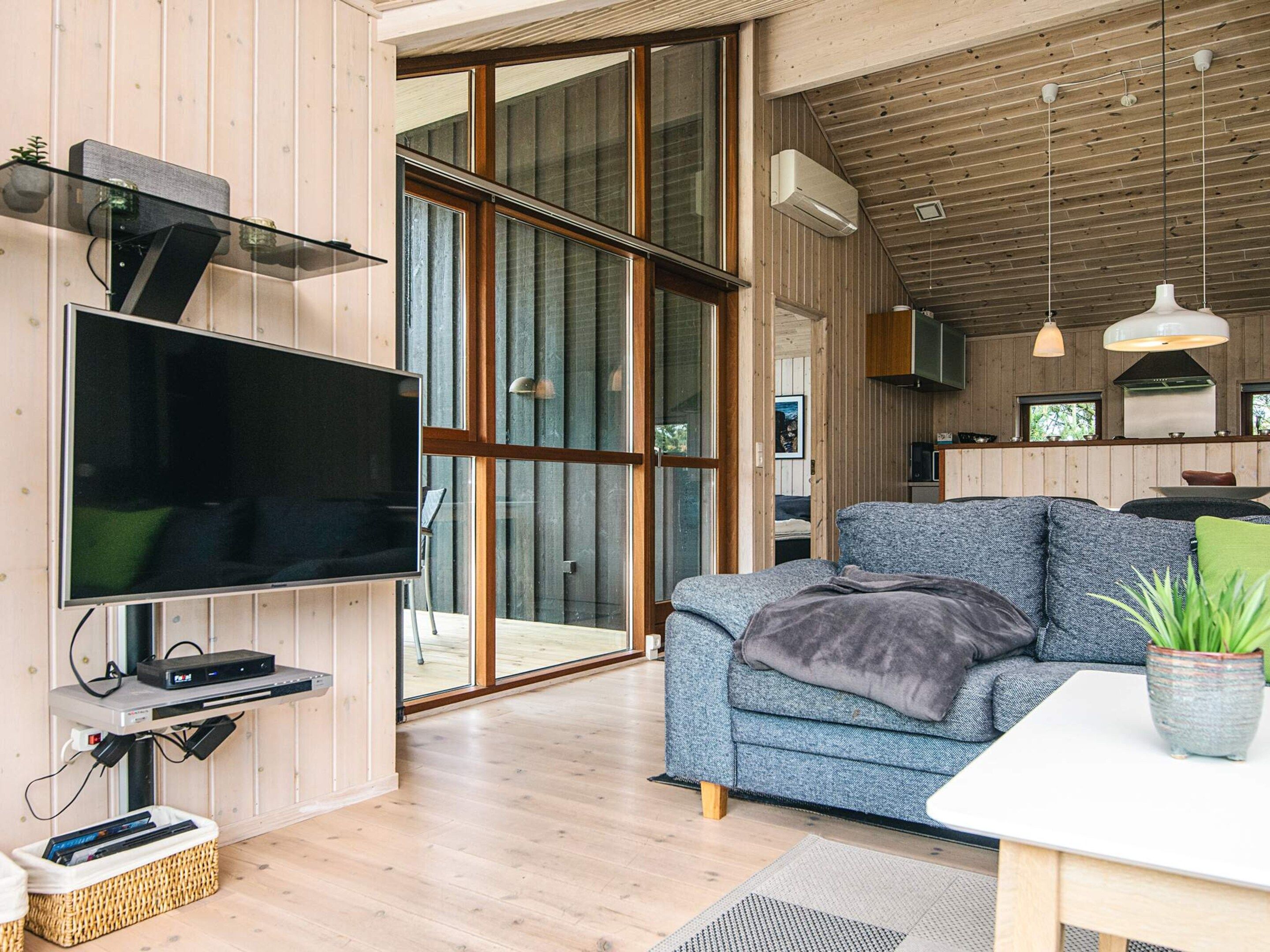 A modern living room with a flat-screen TV, a sofa, and a dining area with a table.