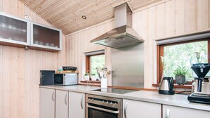 Una cocina moderna con paneles de madera, electrodomésticos de acero inoxidable y un ventanal que proporciona luz natural.