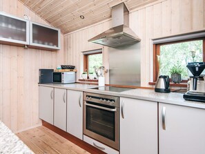 A modern kitchen with wooden paneling, stainless steel appliances, and a window providing natural light. - 4 Star Holiday Home in Hemmet (Hemmet)