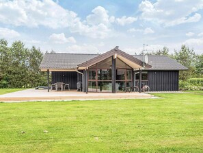 A modern house with a covered patio, large windows, and a well-maintained lawn. - 4 Star Holiday Home in Hemmet (Hemmet)