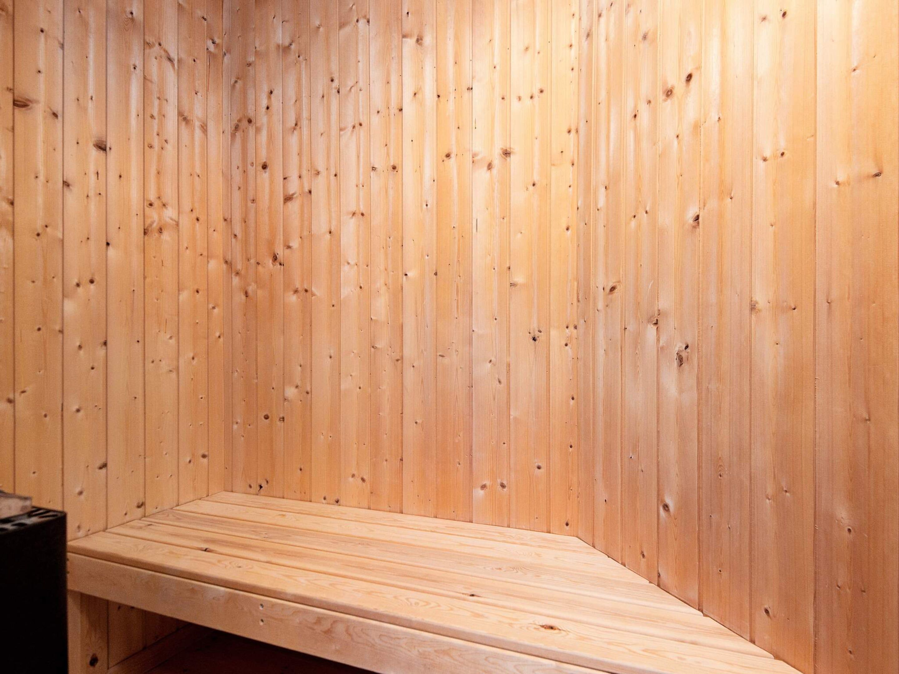 Una sala de sauna con paredes de madera y un banco.
