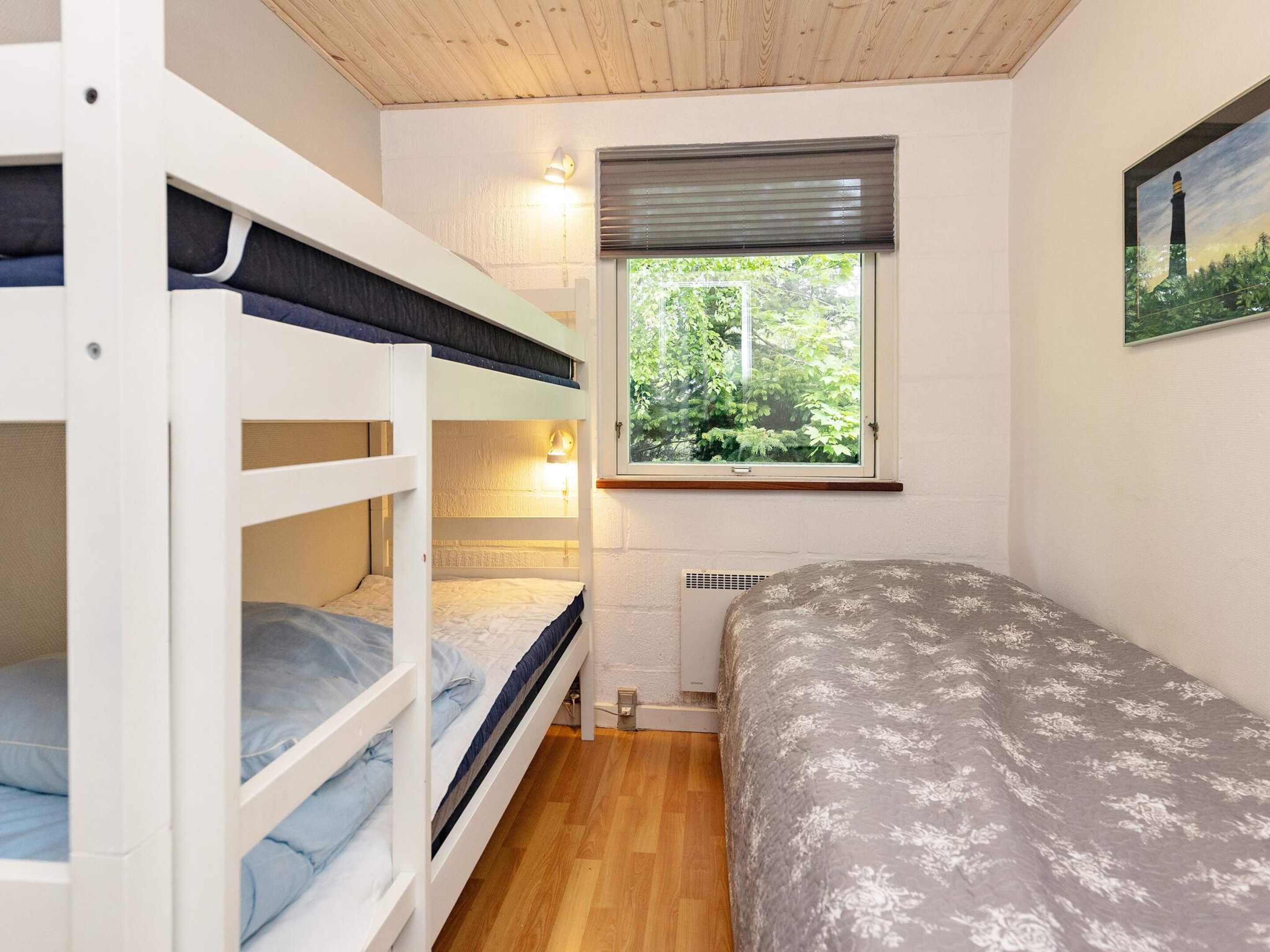 A room with bunk beds, a window with a view of greenery, and a radiator.