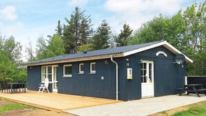 Ein kleines, dunkelblaues Gebäude mit einer Holzterrasse, einer weißen Tür und einer Satellitenschüssel.