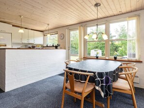 Una cocina con armarios blancos, una mesa de comedor con sillas y un ventanal con vistas a la vegetación.