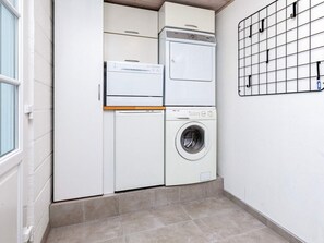 A laundry room with a washing machine, dryer, and stacked cabinets. - 4 Star Holiday Home in Thyholm (Thyholm)