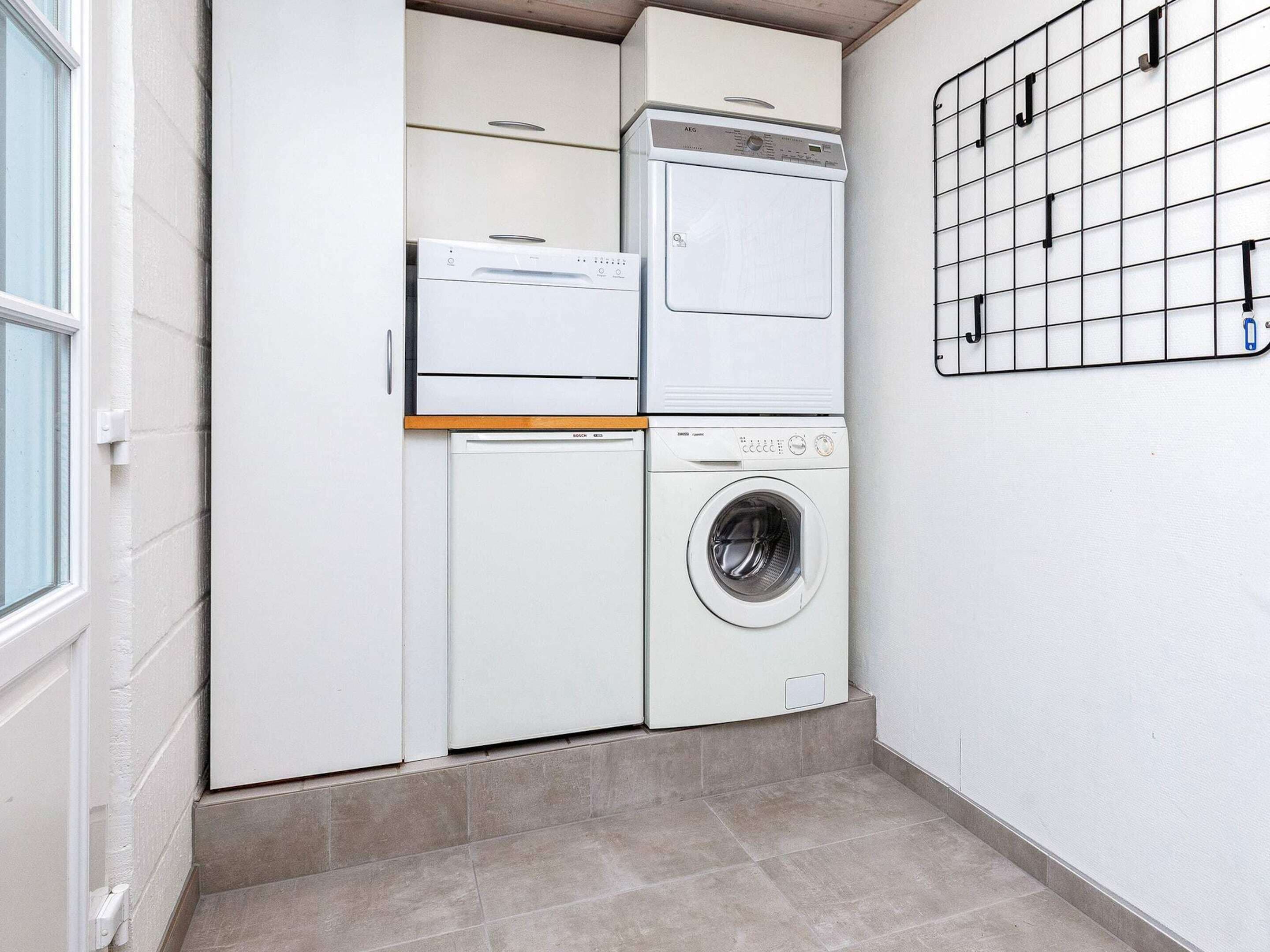 A laundry room with a washing machine and dryer, a tiled floor, and a grid wall.