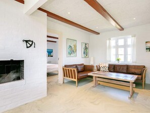 A living room with a fireplace, a sofa set, a coffee table, and artwork on the walls. - 4 Star Holiday Home in Ulfborg (Ulfborg)