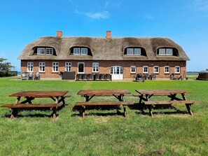 A large brick building with a thatched roof, multiple windows, and outdoor seating. - 4 Star Holiday Home in Ulfborg (Ulfborg)