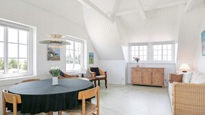 Een ruime loft met een hoge plafond, een eetgedeelte met een ronde tafel en een gezellige zithoek met een bank.