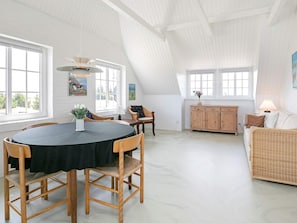 A spacious loft with a high ceiling, a dining area with a round table, and a cozy seating area with a sofa. - 4 Star Holiday Home in Ulfborg (Ulfborg)
