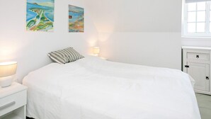 Een slaapkamer met een bed, bedlampen en twee schilderijen aan de muur.