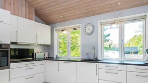Une cuisine moderne avec des armoires blanches, un comptoir noir, un four encastré et une horloge au mur.